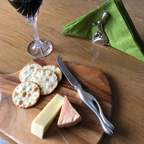 cheesknife on a board with cheese glass of wine and serviette holder