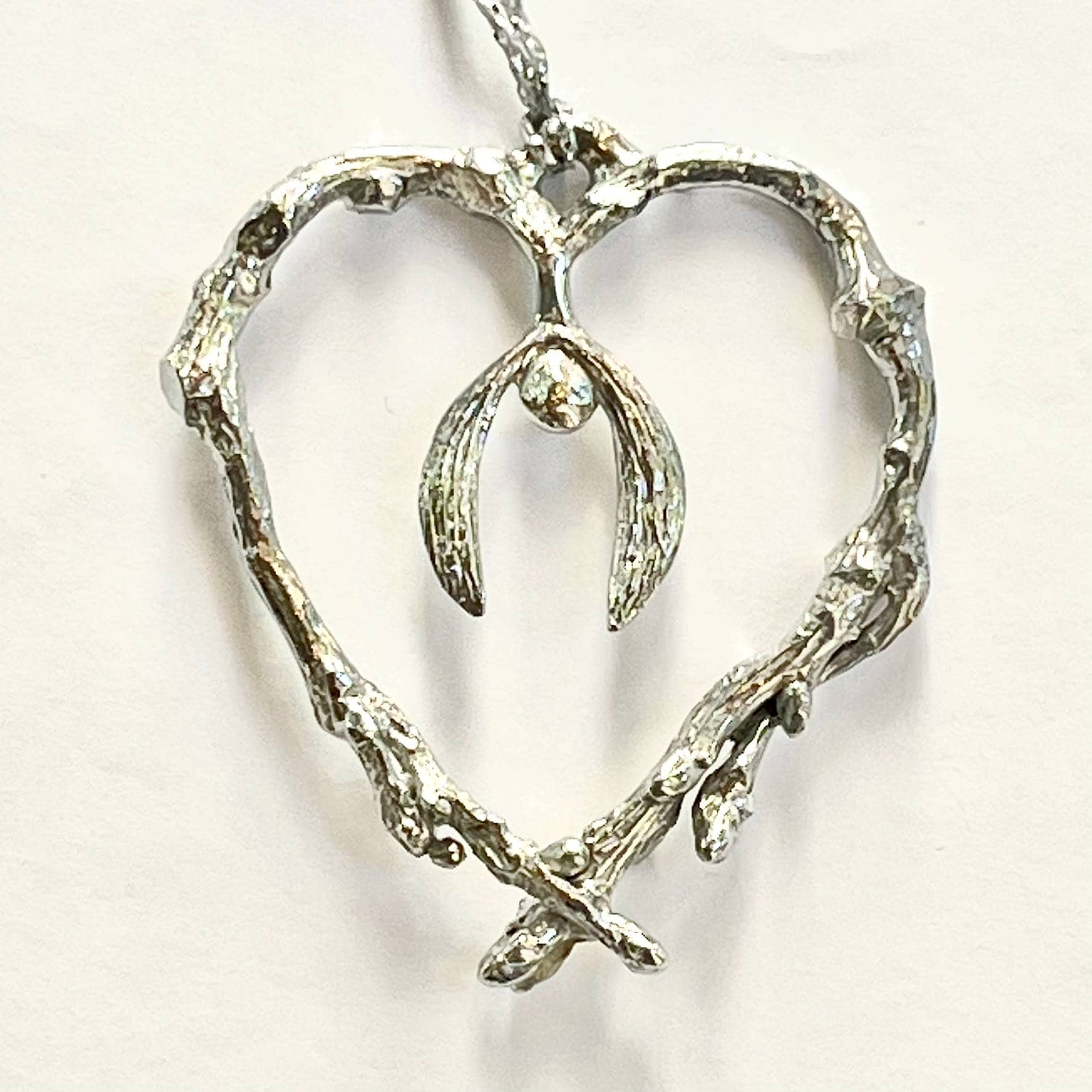 pewter heart made to look like a twig with a sprig of mistletoe in the middle hanging off a silver thread