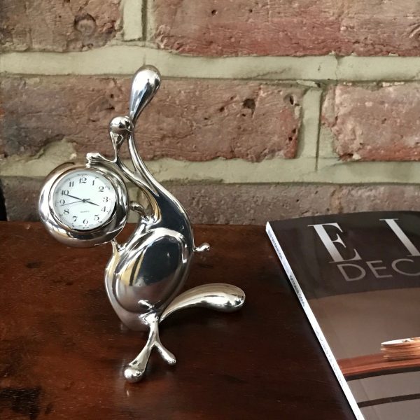 pewter maris clock on wooden box with brick wall in the backgound sat next to a elle decoration magazine