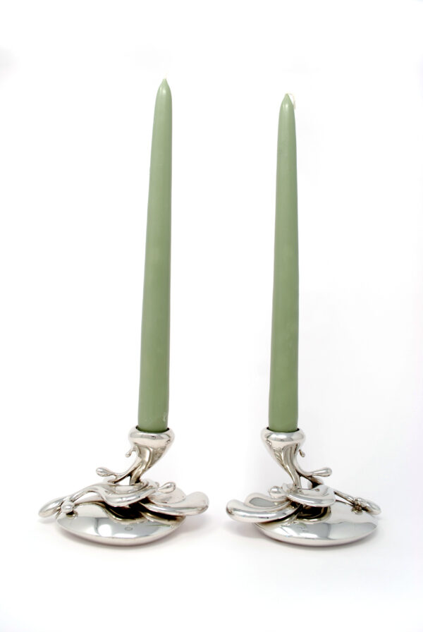 pair of pewter flowing candlestick with sage colour candles in them