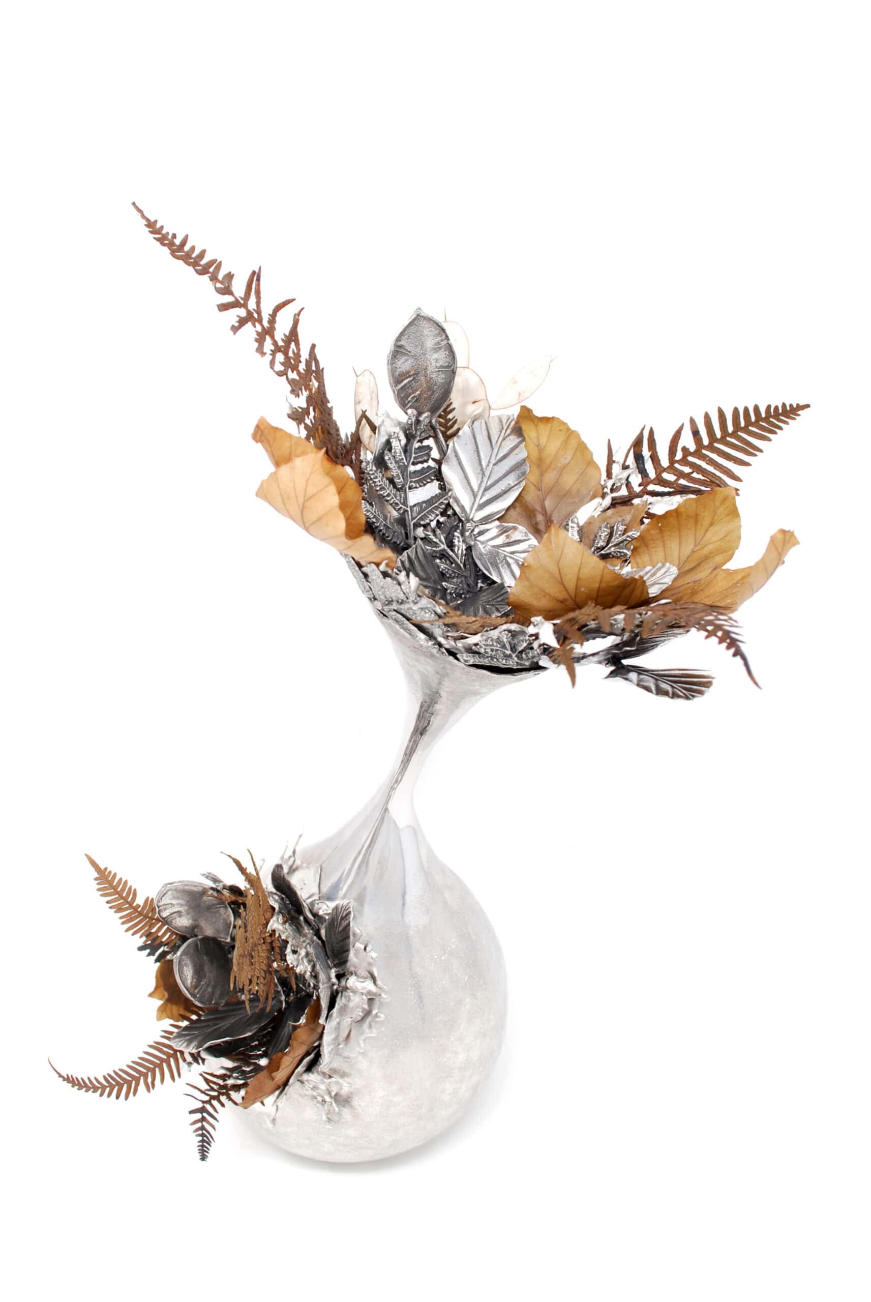 Silent Flourish contemporary hand-raised pewter sculpture by Fleur Grenier featuring preserved woodland botanicals and cast pewter leaves in an elegant flowing vessel.